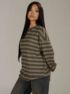 Detail of oversized striped crewneck sweatshirt in autumn earth tones worn by model