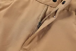 Detail shot of men's khaki cargo shorts showing durable zipper and ripstop fabric.