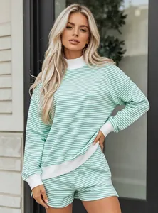 Model wearing a two-piece striped green loungewear set with loose sweatshirt and shorts