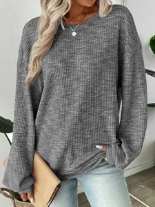 Detailed view of a grey waffle knit loose-fit long sleeve top worn by a model