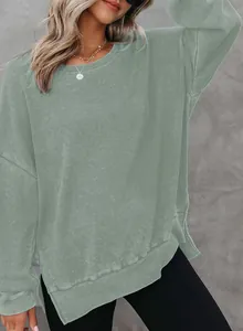 Detail van een saliegroene wafelgebreide sweater met zijsplitjes en lange mouwen