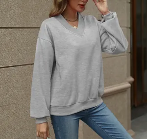 Casual women's grey V-neck sweatshirt with a relaxed fit shown in an urban setting.