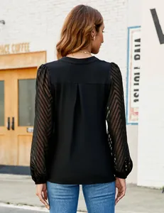Back view of a black chiffon blouse with pleated detail and sheer lace patchwork sleeves.