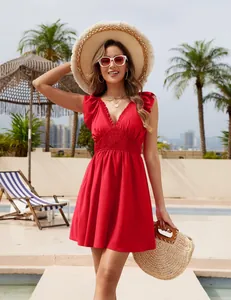 Una donna in abito da spiaggia rosso con scollo a V, maniche a volant e vita a punto smock.