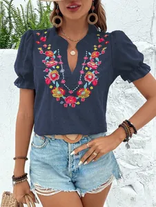 Detalle de la blusa de gasa azul marino con vibrante bordado floral y cuello de pico.