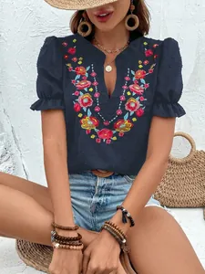Detalle de blusa de chifón azul marino con bordado floral y mangas abullonadas.