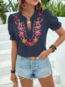Detalle de blusa de gasa azul marino con bordados florales y mangas abullonadas con cuello en V.