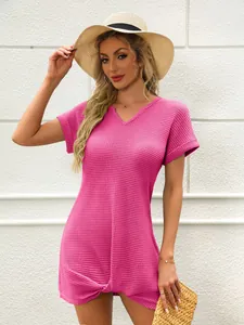 Dettaglio di un copricostume in maglia a nido d'ape rosa con scollo a V e nodo decorativo