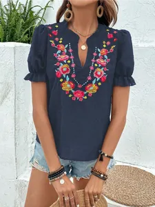 Vista detallada del bordado floral de colores en una blusa azul marino con cuello en V