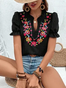 Detalle de blusa de gasa negra con cuello en V, bordado floral y mangas abullonadas.