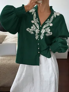 Detailaufnahme der eleganten weißen Blumenstickerei auf dieser grünen Langarmbluse