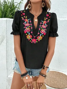 Detalle del bordado floral en blusa negra con cuello en V y mangas abullonadas