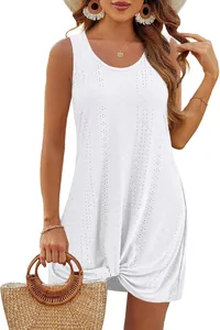Close-up of white hollow-out beach vacation dress with knot detail and straw bag.