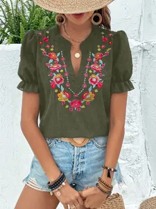 Detalle del bordado floral en una blusa de gasa verde con cuello en V y mangas abullonadas.