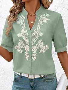 Detail view of white floral embroidery on a sage green cotton short-sleeved casual shirt.