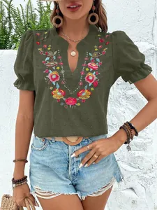 Primer plano del bordado floral en una blusa de gasa verde oliva con cuello en pico.