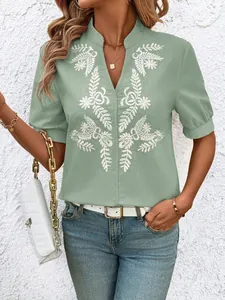 Close-up of a women's sage green cotton V-neck shirt featuring white floral embroidery detail