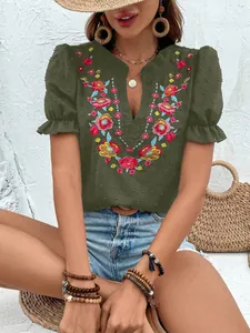 Detalle de blusa de gasa verde oscuro con cuello en V, bordado floral y mangas abullonadas.