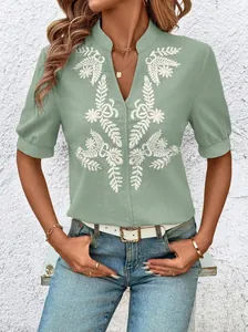 Intricate white floral embroidery detail on a sage green V-neck cotton blouse for women