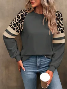 Détail du patchwork léopard et des rayures beiges sur un sweat-shirt gris foncé à manches