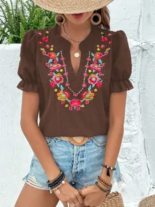 Detalle de bordado floral de colores en blusa marrón de gasa con cuello en V