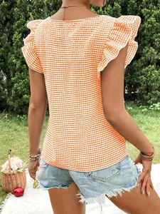 Close-up back view of an orange gingham top featuring stylish ruffle sleeves outdoors