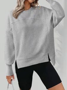 Détail d'un sweat gris à col rond présentant une coupe ample et des fentes latérales stylées