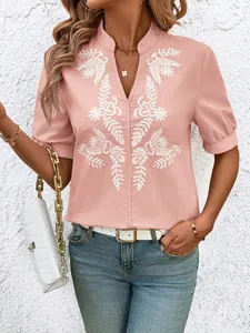 Detail showing the white floral embroidery on a pink V-neck short sleeve cotton shirt