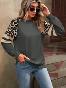 Détail du patchwork léopard et des manches colorées sur un sweat gris