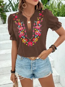 Detalle de blusa de gasa marrón con cuello en V, bordado floral vibrante y mangas abullonadas.