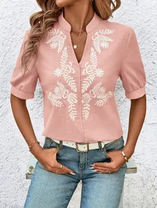 Close-up of elegant pink V-neck blouse with intricate white floral embroidery detail