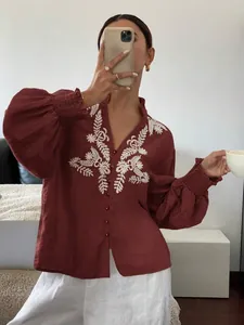 Detail von weinrotem Langarmshirt mit weißer Blumenstickerei und gerafften Bündchen