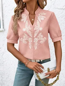 Detail of pink cotton V-neck shirt featuring intricate white floral embroidery.