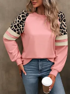 Gros plan d'un sweat-shirt rose avec épaules imprimé léopard et rayures blanches