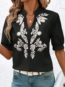 Close-up of black cotton blouse featuring elegant white floral leaf embroidery and V-neck.