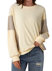 Detail shot of a cream round-neck sweatshirt with striped patchwork sleeves.