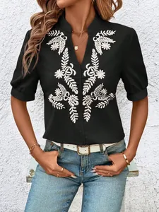 Close-up detail of white leaf embroidery on black V-neck cotton shirt for women