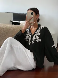 Detailansicht eines schwarzen Langarmshirts mit eleganter weißer Blumenstickerei