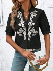 Detailed view of a black cotton shirt featuring elegant white floral embroidery