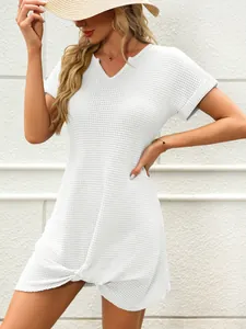 Dettaglio di un abito da spiaggia bianco in maglia a nido d'ape con scollo a V e nodo.