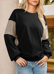 Close-up detail of women's black sweatshirt with stylish striped patchwork sleeve panels