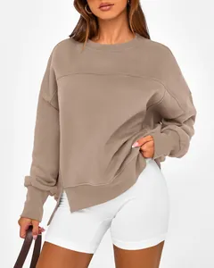 Détail d'un sweat-shirt taupe ample à col rond avec fentes latérales porté par un mannequin.