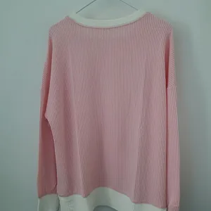 Back view detail of a pink long sleeve sweatshirt featuring white contrast ribbed trim