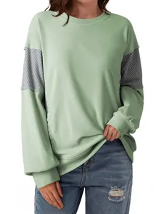 Close-up detail of the mint green sweatshirt featuring striped patchwork sleeve accents