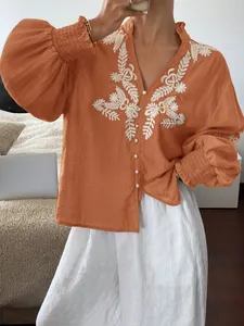 Detail der orangefarbenen bestickten Bluse mit Blumenmuster und Puffärmeln