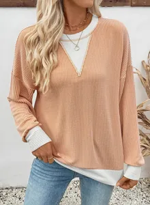 Detail view of the loose waffle knit top featuring a chic color-block design in apricot and white.