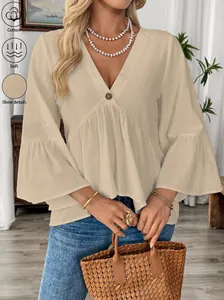 Elegante beige Baumwollbluse mit V-Ausschnitt und Rüschenärmeln im Lifestyle-Ambiente.
