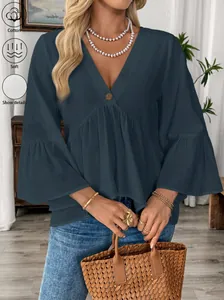Detailansicht der weichen Baumwolltextur der dunkelblauen V-Ausschnitt Bluse mit Rüschen.