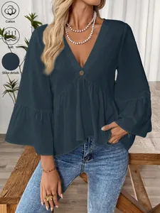 Detail der dunkelblauen Baumwollbluse mit V-Ausschnitt und eleganten Volantärmeln.
