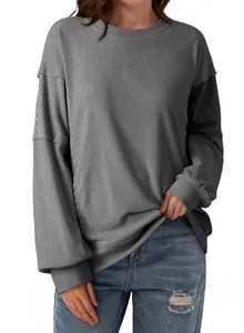 Close-up of casual grey crewneck sweatshirt featuring striped patchwork sleeve details